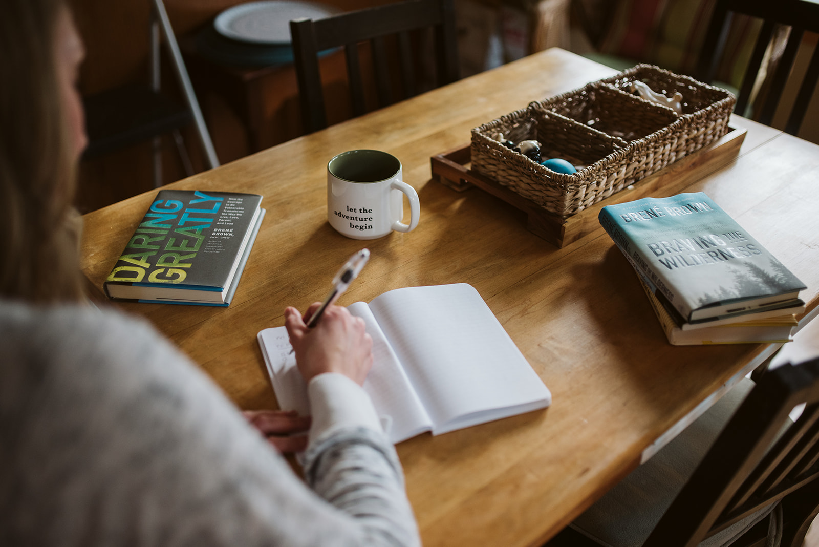 Shawn journaling at a sunlit wooden table beside books and a warm mug